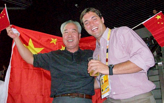 Beijing Olympics (2008): Sam is inside the “Bird’s Nest” stadium with a friendly Chinese man after watching Usain Bolt break the world record in the 100m.